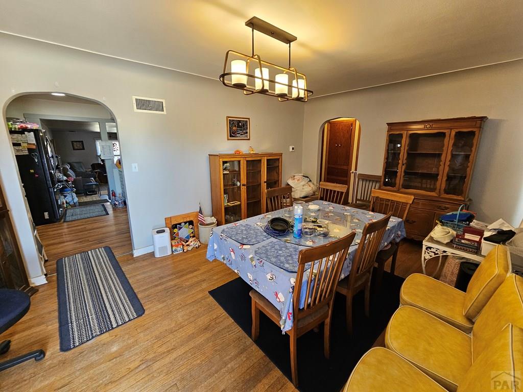 233 East 5th Avenue Springfield, CO 81073 - Photo 2 of 30 a dining room with wooden floor a chandelier a wooden table and chairs