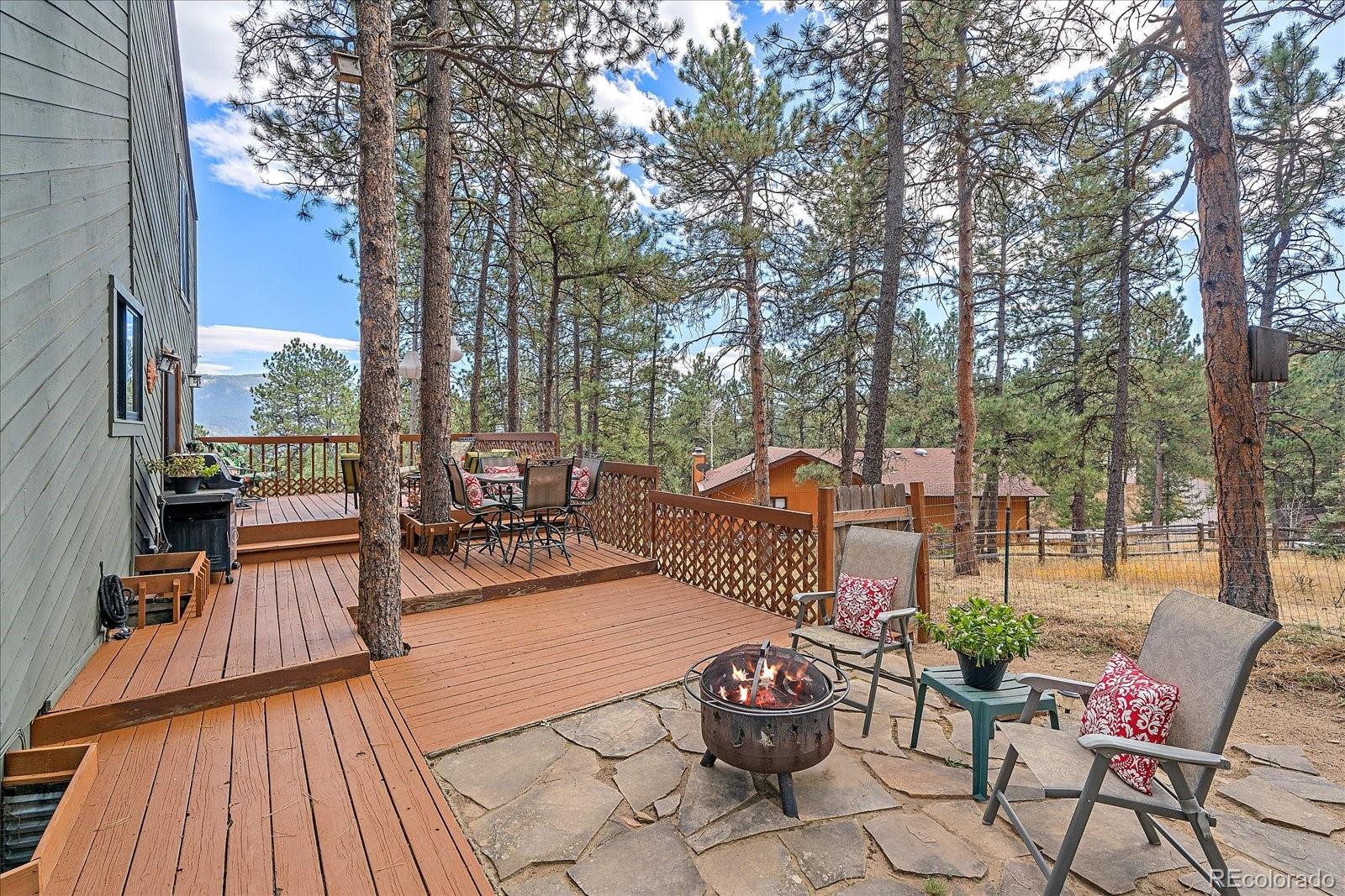 4059 Histead Way Evergreen, CO 80439 - Photo 19 of 37 a view of a patio with dining table and chairs with wooden floor and fence