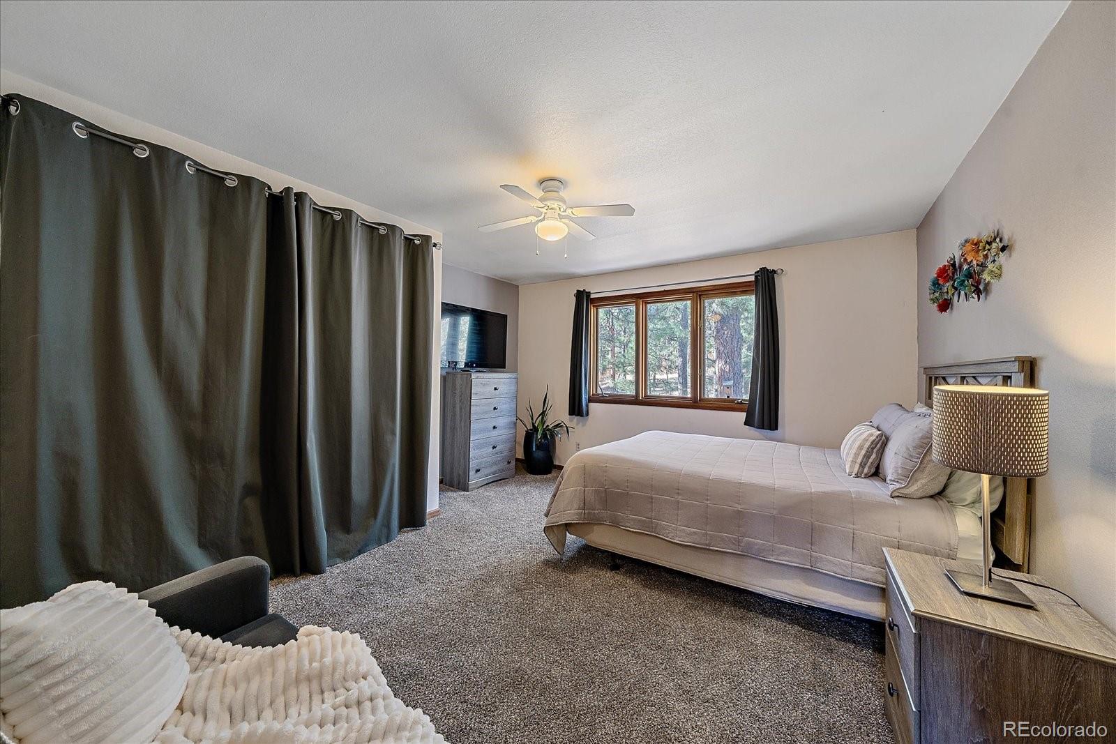 4059 Histead Way Evergreen, CO 80439 - Photo 28 of 37 a bedroom with a bed and a chandelier