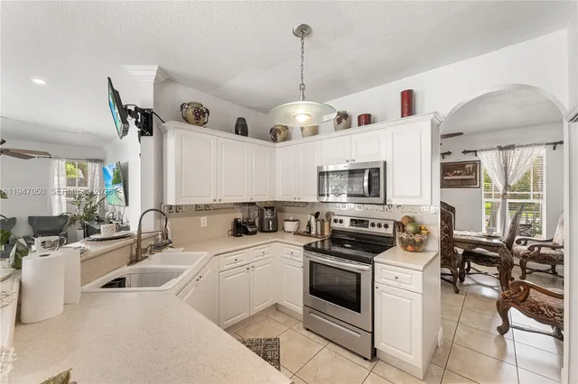 a kitchen that has a lot of white cabinets and stainless steel appliances