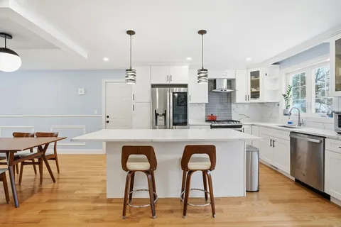 a kitchen with stainless steel appliances granite countertop a sink a stove a refrigerator and island with wooden floor