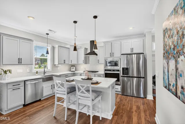 a kitchen with stainless steel appliances kitchen island granite countertop a sink stove and refrigerator