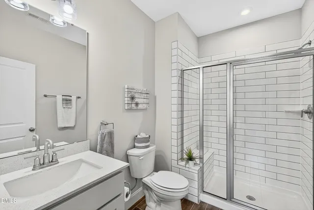 a bathroom with a sink a toilet a mirror and shower