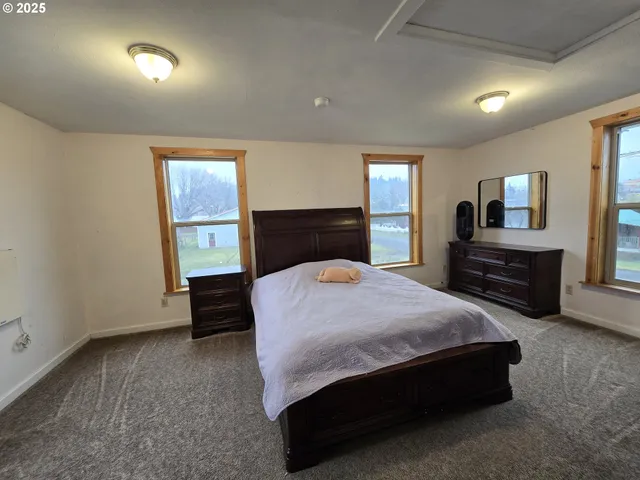a spacious bedroom with a bed and a dresser next to a window