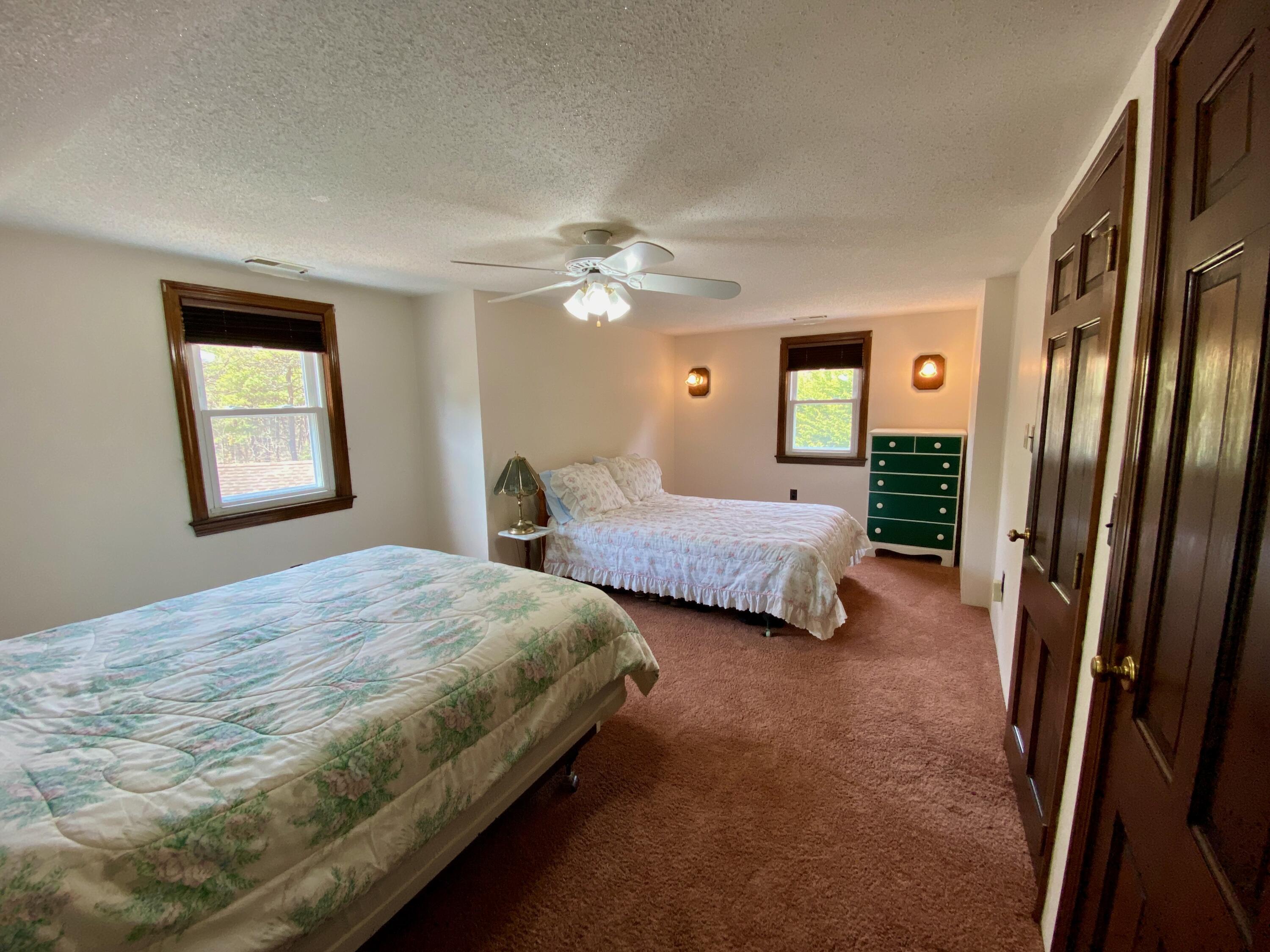 380 Foxwood Drive Eastham, MA 02642 - Photo 17 of 37 a bedroom with two beds and a chandelier