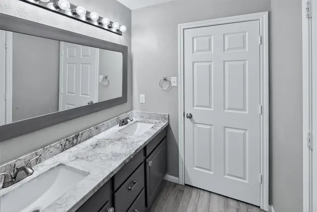 a bathroom with a granite countertop double vanity sink mirror and
