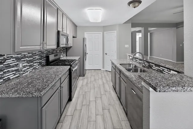 a kitchen with stainless steel appliances granite countertop a stove refrigerator and microwave