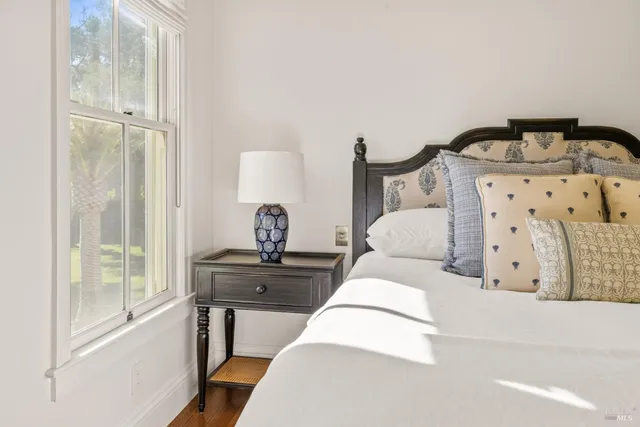 a bedroom with a bed potted plant on dresser next to a window