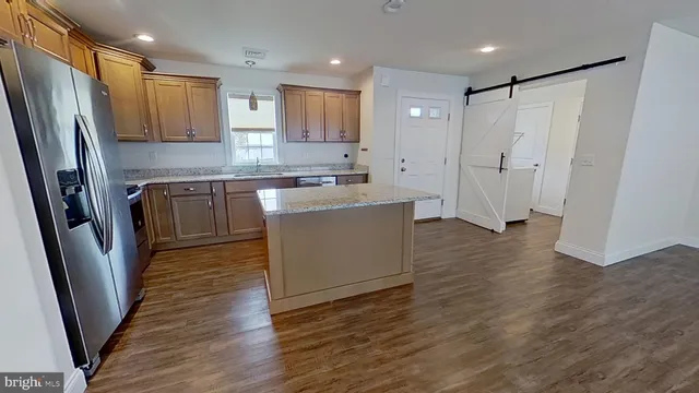 a kitchen with stainless steel appliances granite countertop a refrigerator a sink a stove a microwave and wooden floor