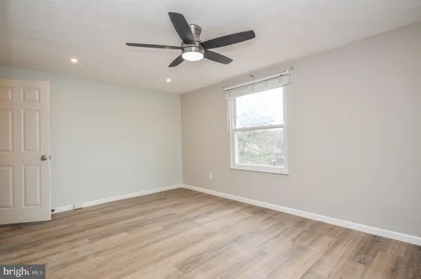 an empty room with wooden floor fan and windows