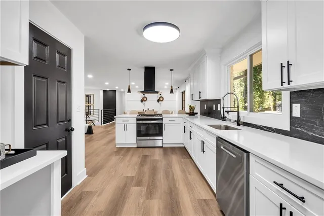 a large kitchen with stainless steel appliances kitchen island granite countertop a large counter top a stove a sink dishwasher and a refrigerator