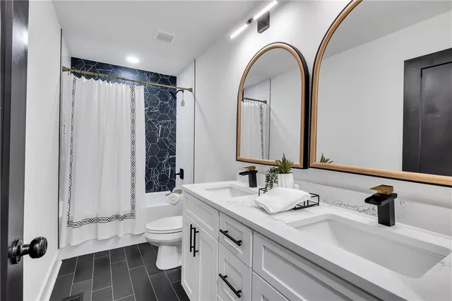 a bathroom with a double vanity sink toilet and a mirror