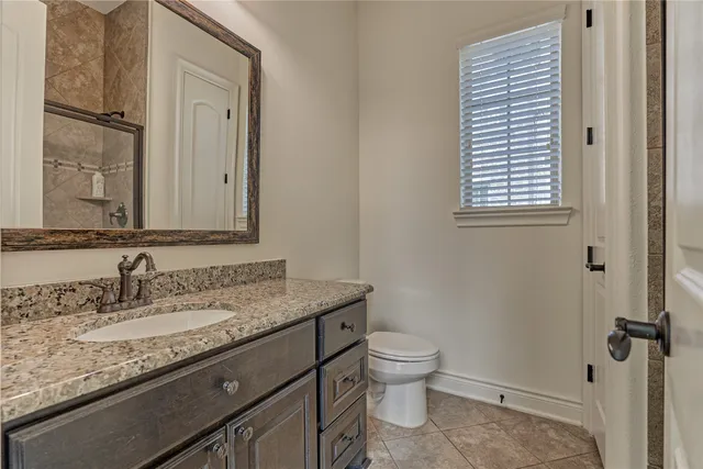 a bathroom with a granite countertop sink toilet and mirror