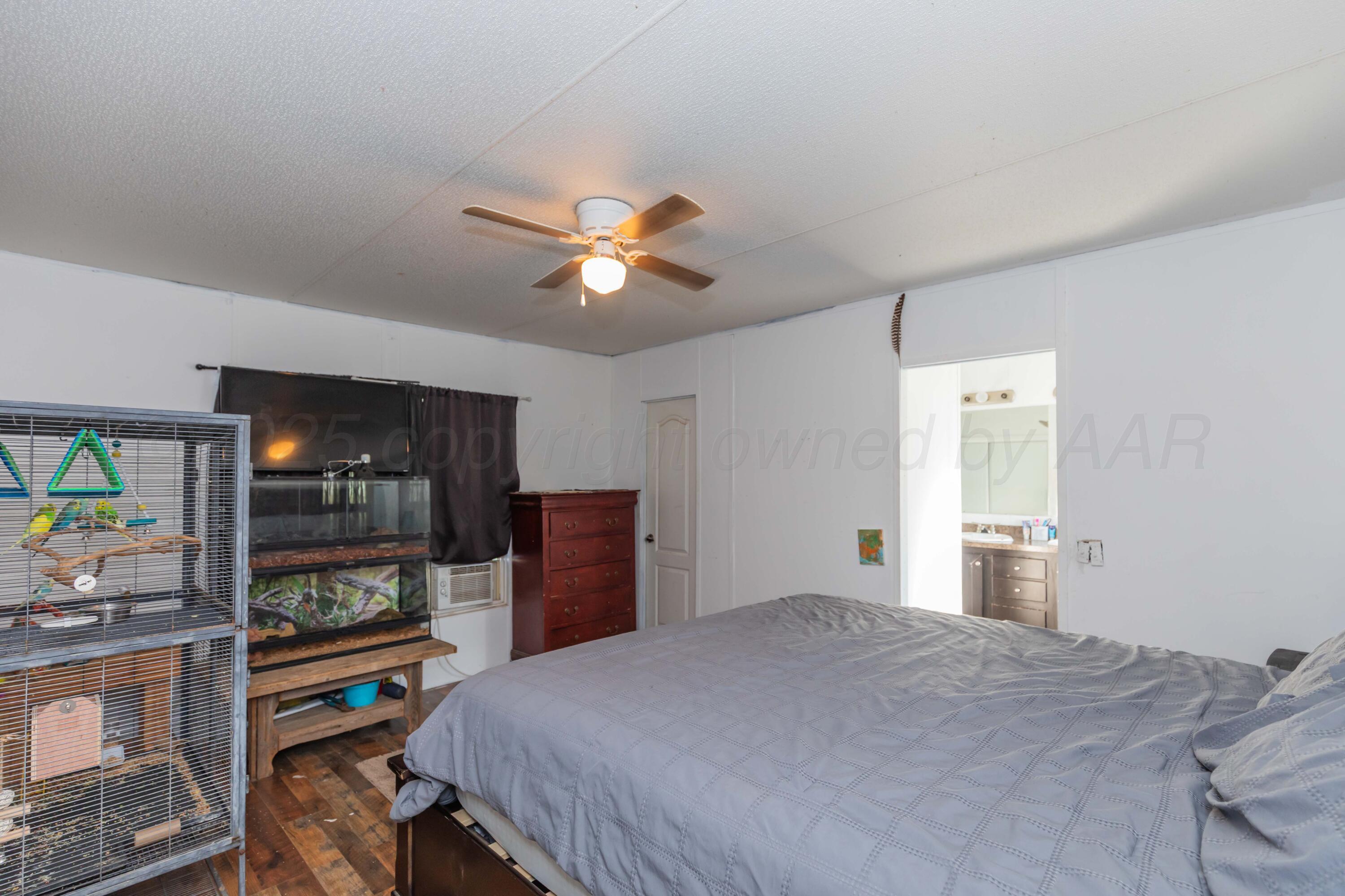 11566 County Road East Pampa, TX 79065 - Photo 14 of 56 a bedroom with a bed and a chandelier