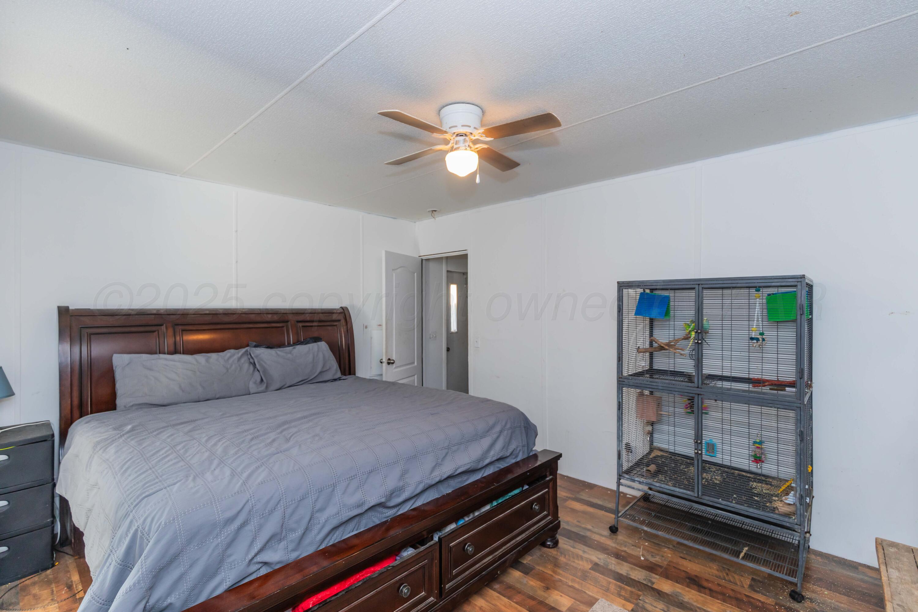 11566 County Road East Pampa, TX 79065 - Photo 15 of 56 a bedroom with a bed and a chandelier