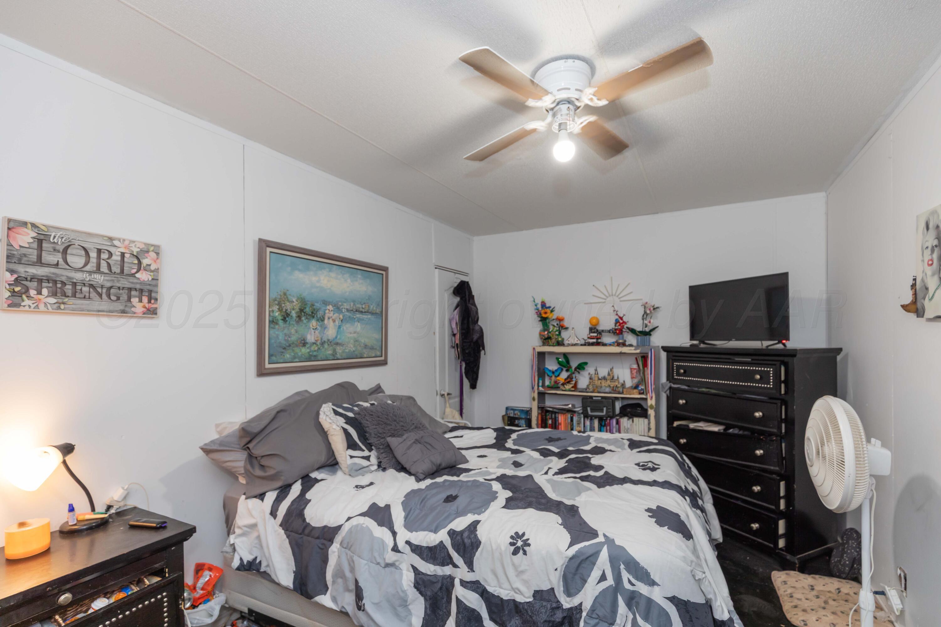 11566 County Road East Pampa, TX 79065 - Photo 22 of 56 a bedroom with a bed and a chandelier