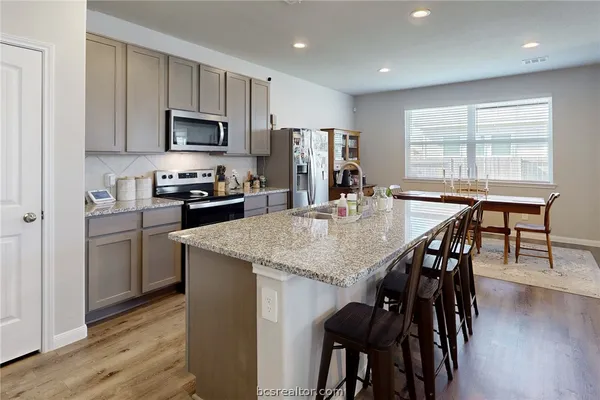 a kitchen with stainless steel appliances granite countertop a kitchen island hardwood floor and a stove top oven