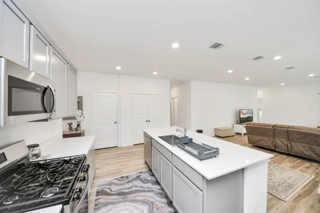 a large kitchen with stainless steel appliances a large counter top and a stove top oven