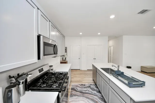 a kitchen with stainless steel appliances a sink stove and cabinets