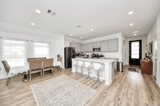 a large white kitchen with wooden floor and stainless steel appliances