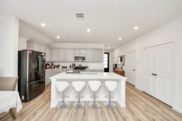 a large kitchen with a table chairs refrigerator and wooden floor