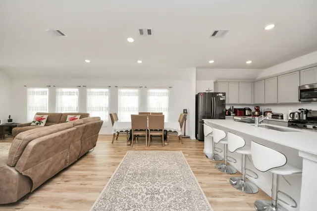 a living room with stainless steel appliances furniture cabinets and a table