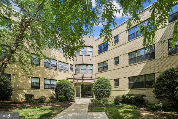 a front view of a multi story residential apartment building with yard and green space