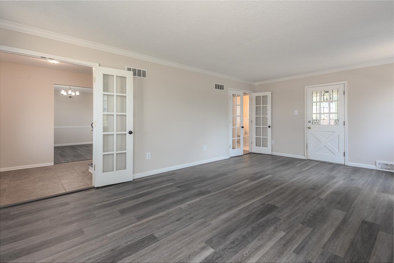 2718 Kate Bond Road Memphis, TN 38133 - Photo 18 of 39 Unfurnished living room with french doors, ornamental molding, dark wood-type flooring, a chandelier, and a textured ceiling