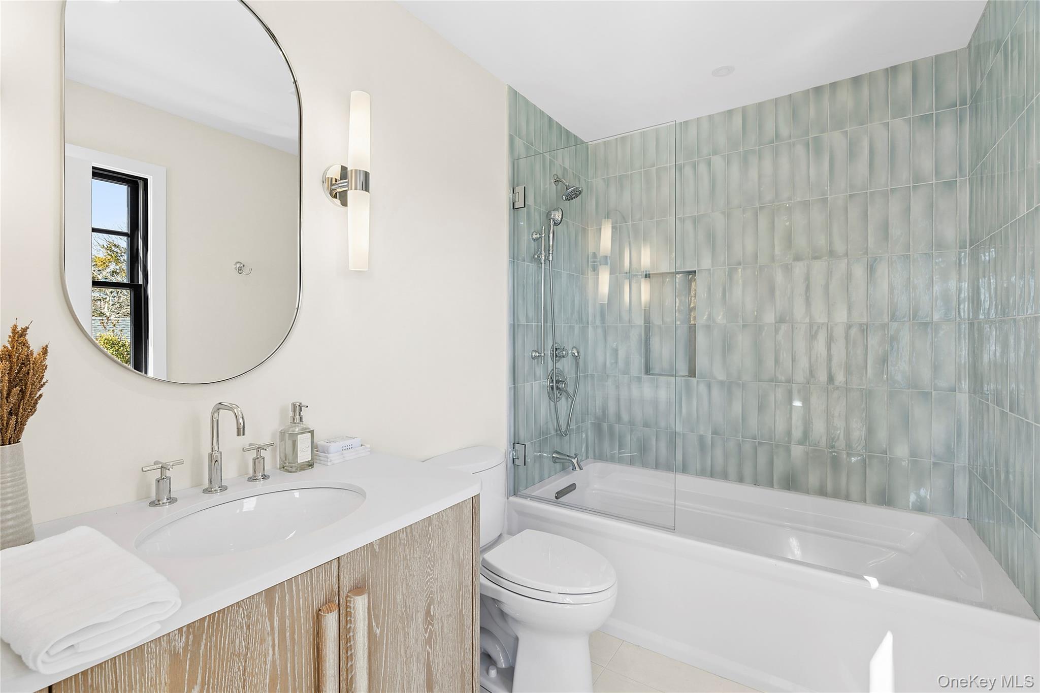54 Library Avenue Westhampton Beach, NY 11978 - Photo 7 of 21 a bathroom with a sink a toilet a mirror a bathtub and shower