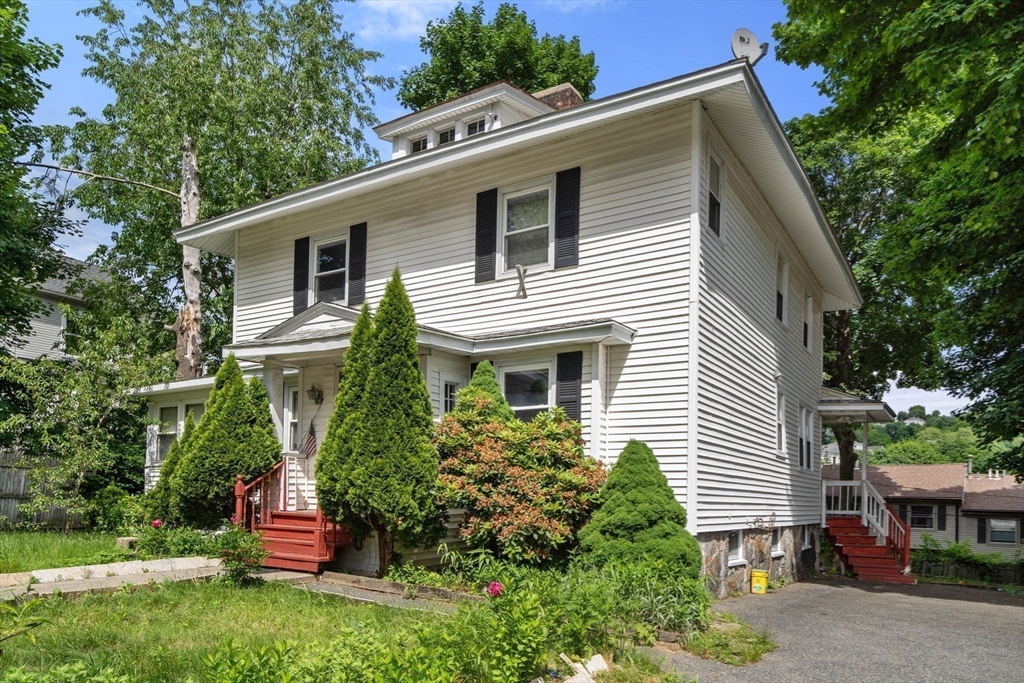 a view of house with a yard and potted plants