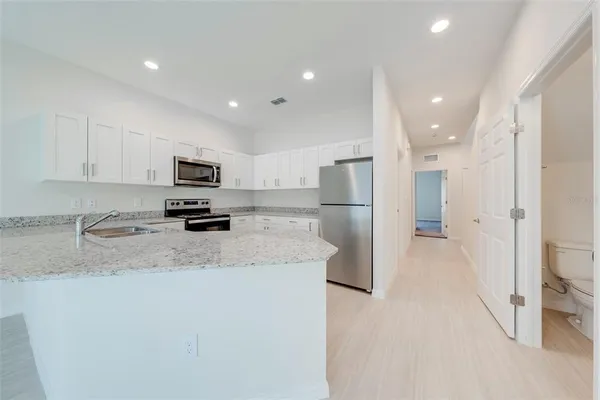 a kitchen with stainless steel appliances granite countertop a refrigerator a stove a sink a microwave a oven and white cabinets