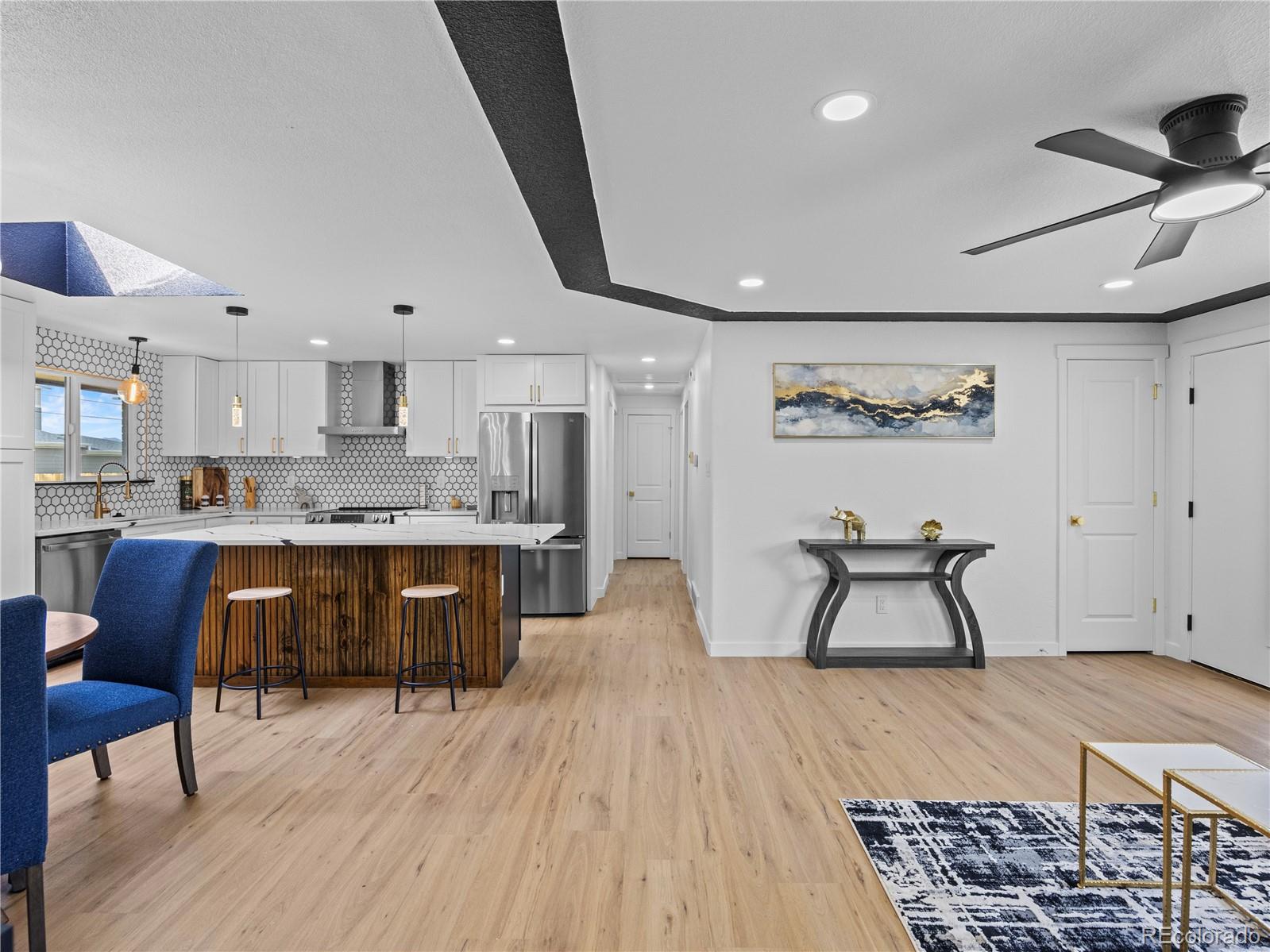 5673 Johnson Street Arvada, CO 80002 - Photo 11 of 40 a kitchen with stainless steel appliances granite countertop a stove a sink a refrigerator and white cabinets with wooden floor