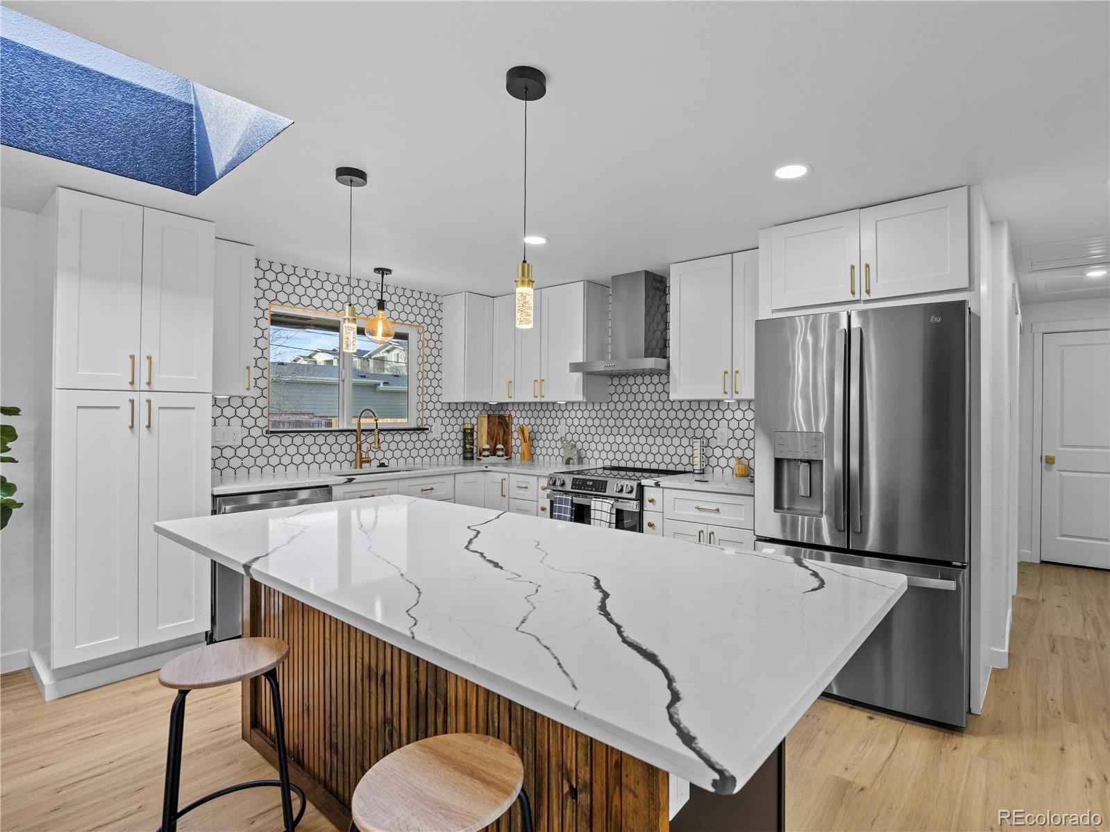5673 Johnson Street Arvada, CO 80002 - Photo 13 of 40 a kitchen with stainless steel appliances granite countertop a sink a stove a refrigerator and island with wooden floor