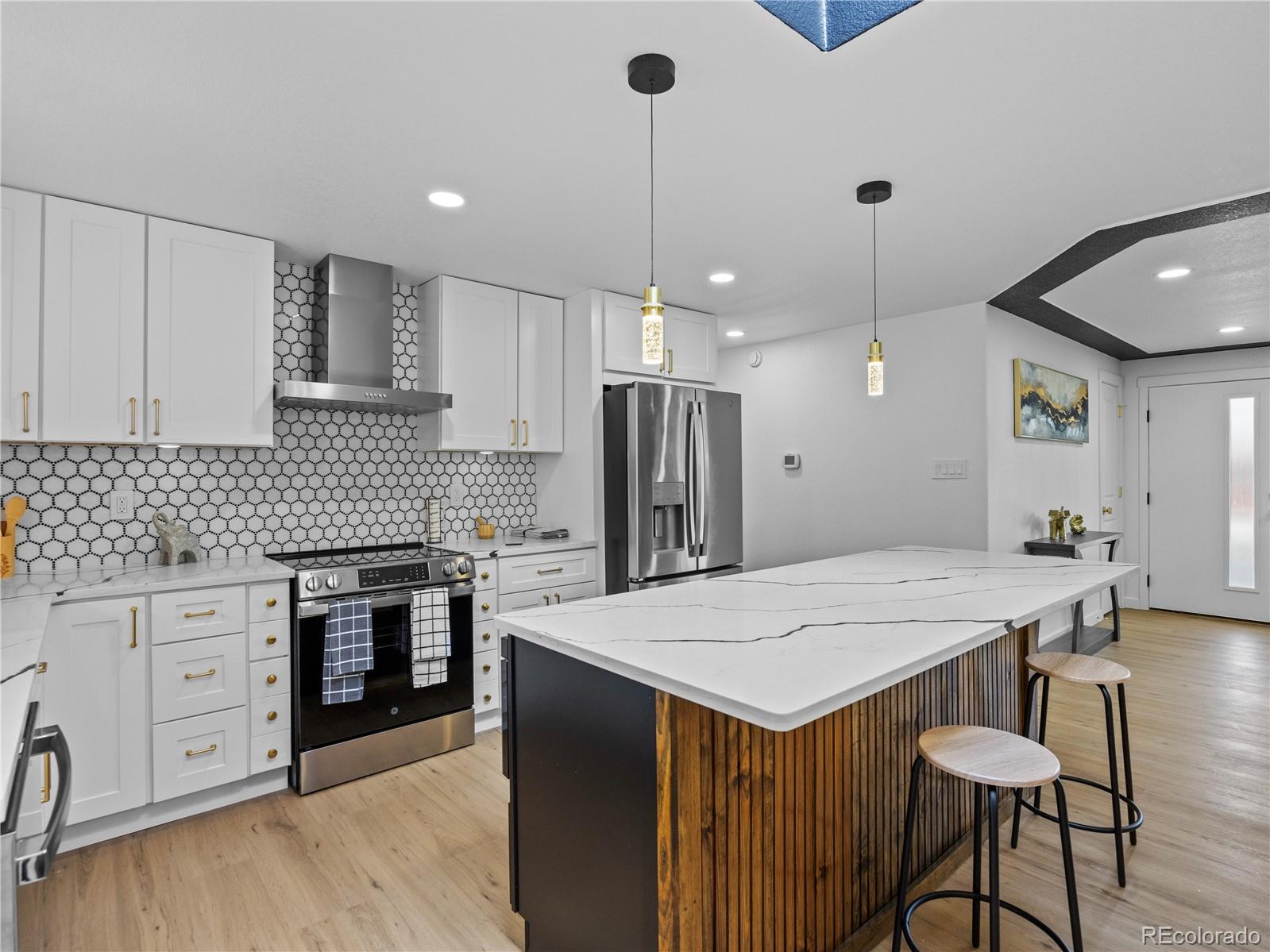 5673 Johnson Street Arvada, CO 80002 - Photo 15 of 40 a kitchen with a stove a refrigerator a sink and chairs