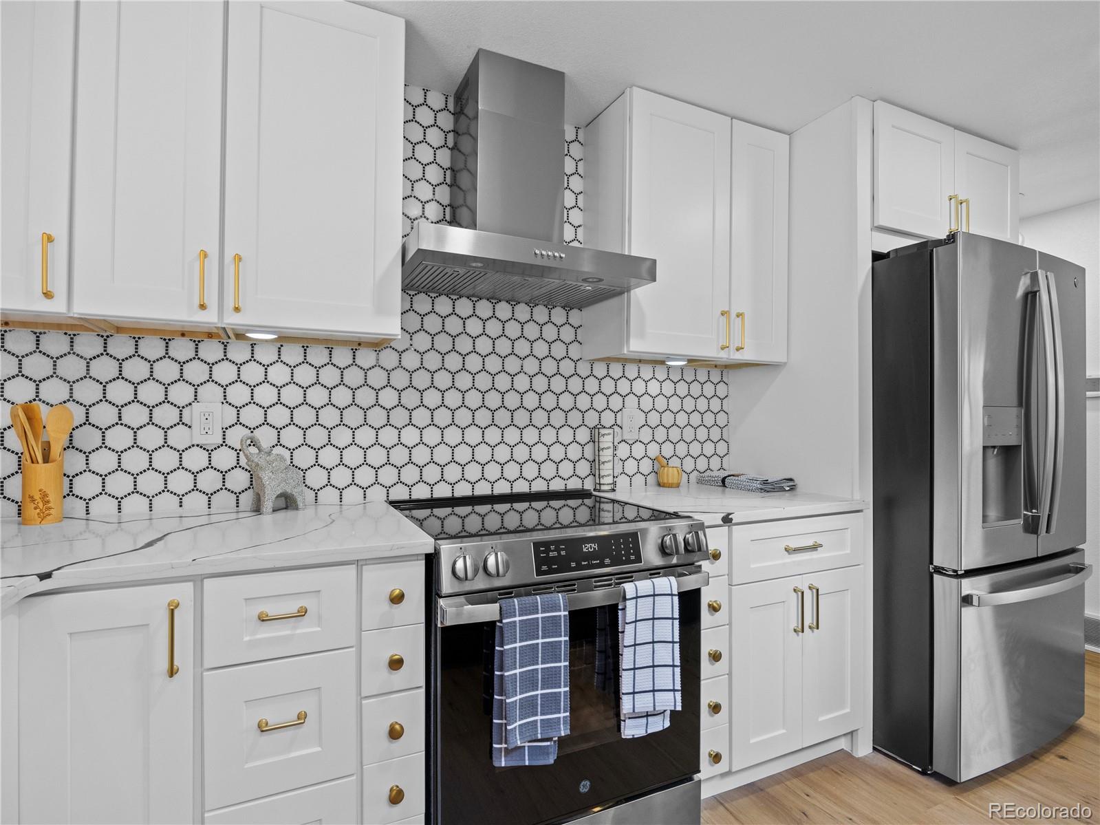 5673 Johnson Street Arvada, CO 80002 - Photo 16 of 40 a kitchen with granite countertop a stove and a refrigerator