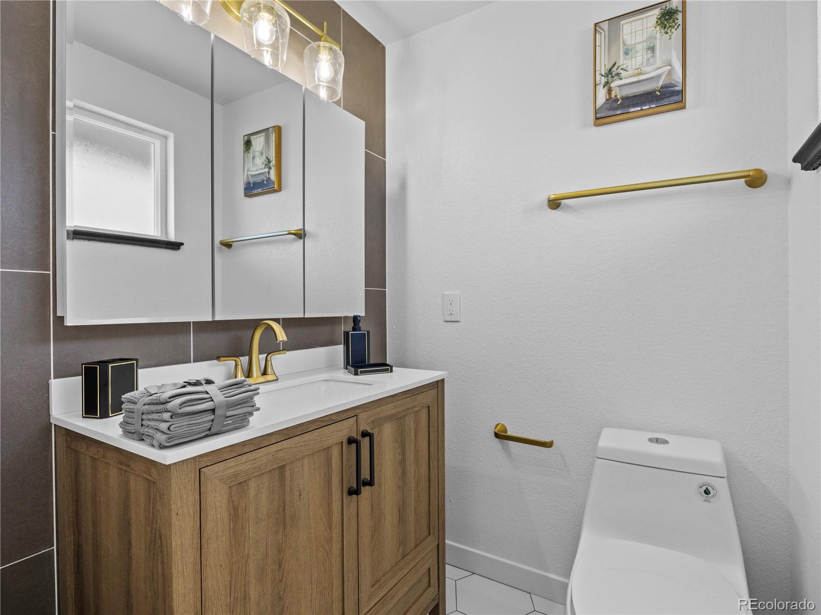 5673 Johnson Street Arvada, CO 80002 - Photo 22 of 40 a bathroom with a granite countertop sink a toilet and a mirror
