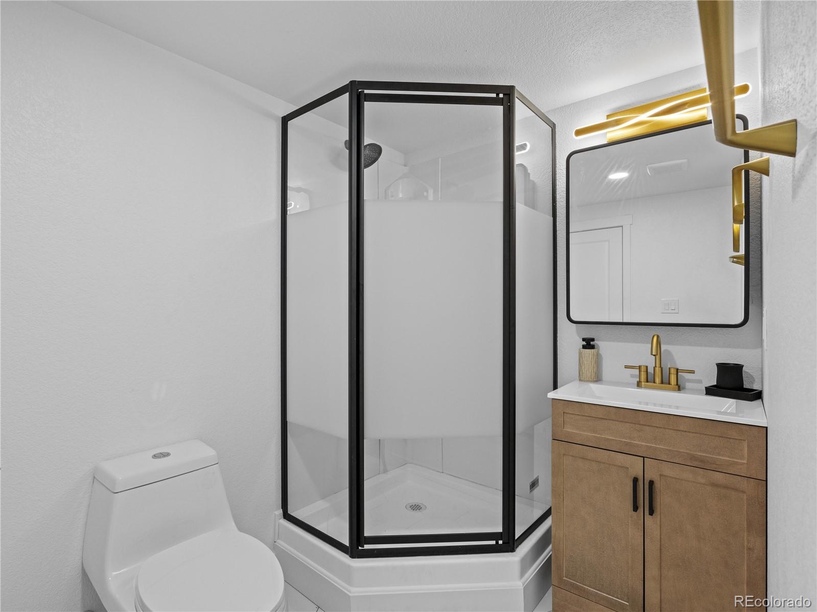 5673 Johnson Street Arvada, CO 80002 - Photo 31 of 40 a bathroom with a toilet a sink and mirror