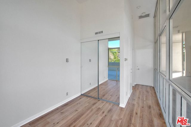 a view of a hallway with wooden floor and a bathroom