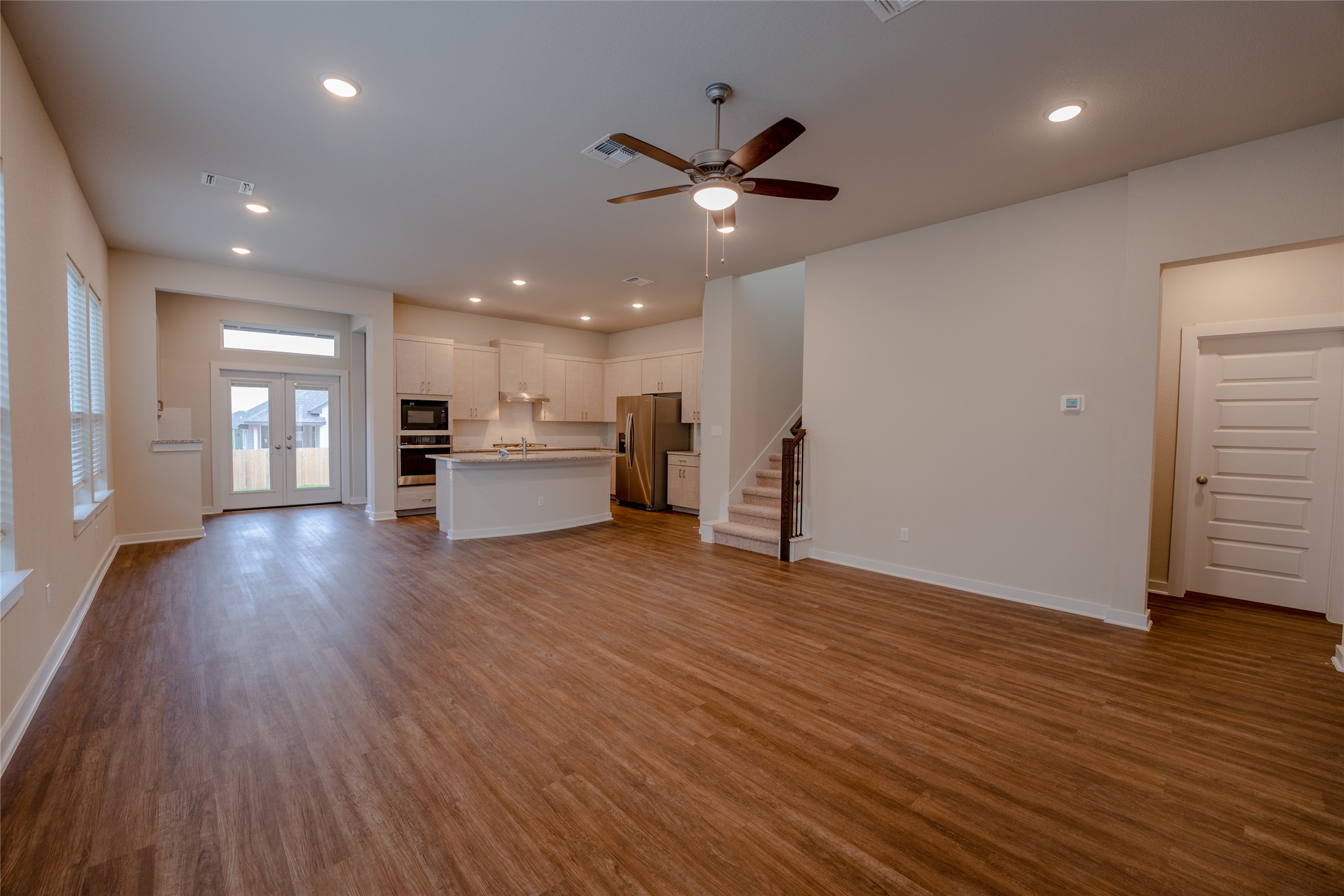 133 High Plains Drive Georgetown, TX 78628 - Photo 11 of 38 an empty room with wooden floor ceiling fan and kitchen view