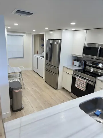 a kitchen with stainless steel appliances a sink dishwasher a stove top oven a refrigerator and a oven