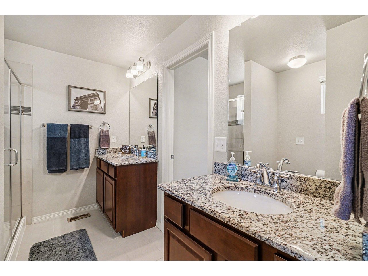 107 South 8th Street Berthoud, CO 80513 - Photo 19 of 22 a bathroom with a granite countertop sink a mirror a vanity and shower
