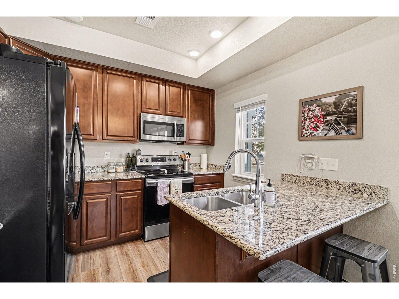 107 South 8th Street Berthoud, CO 80513 - Photo 6 of 22 a kitchen with kitchen island granite countertop a stove top oven microwave and refrigerator