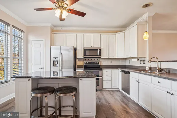 a kitchen with kitchen island granite countertop a sink a counter top space and stainless steel appliances