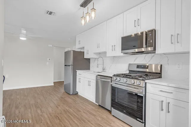 a kitchen with stainless steel appliances white cabinets a stove a sink and a microwave