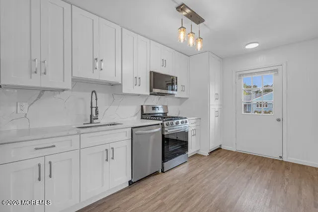 a kitchen with granite countertop a sink cabinets and stainless steel appliances