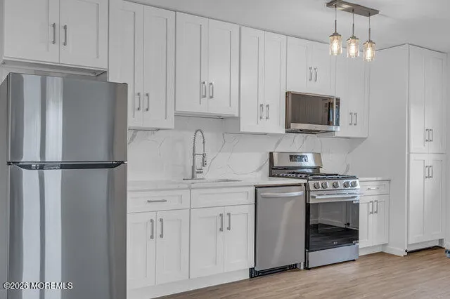 a kitchen with white cabinets and stainless steel appliances