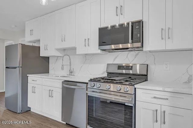 a kitchen with stainless steel appliances white cabinets and a stove a oven with white countertops