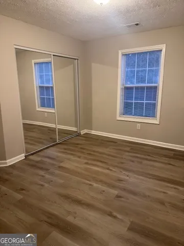 an empty room with wooden floor cabinets and windows