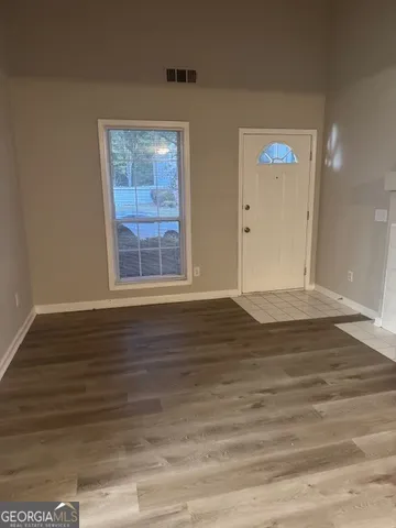 a view of an empty room with wooden floor and a window