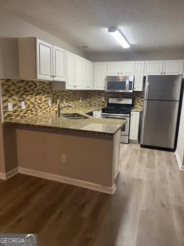 a kitchen with granite countertop a refrigerator and a stove top oven